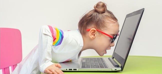 Anak berkacamata bersandar ke laptop