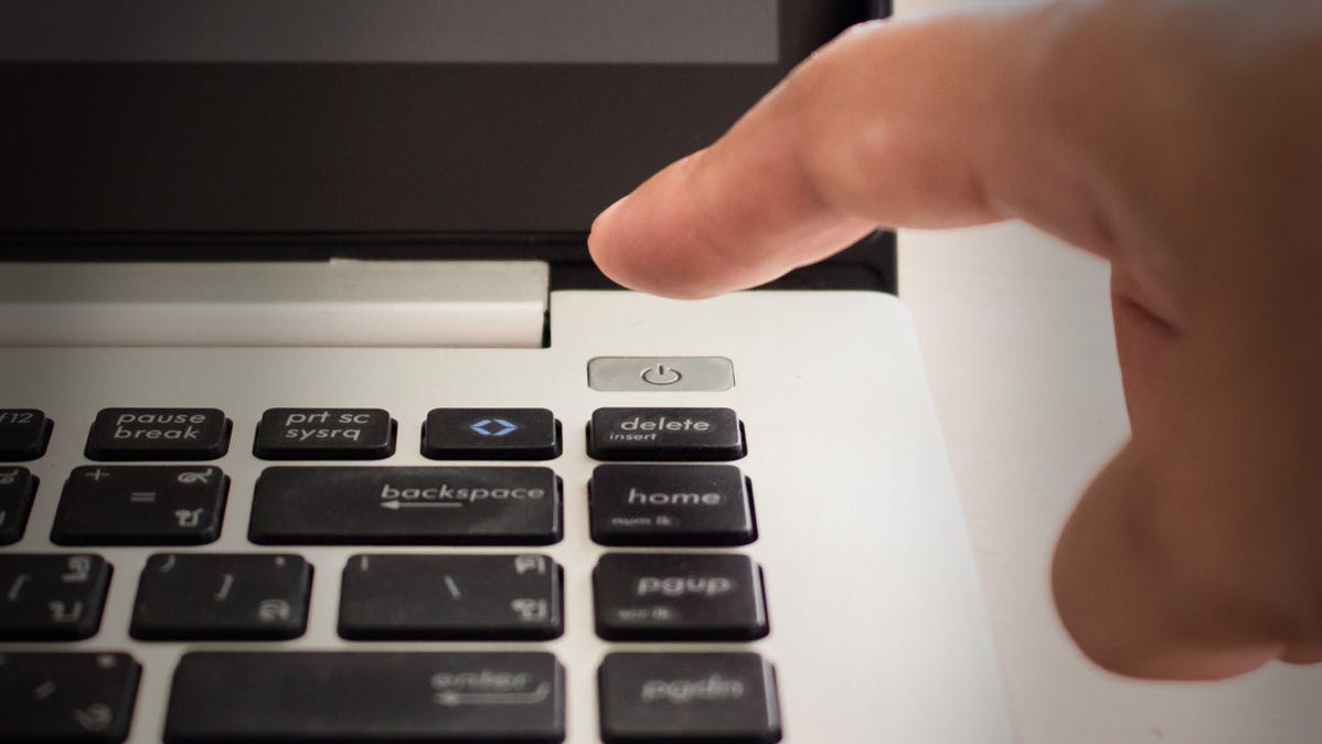 Sebuah jari hendak menekan tombol power laptop.