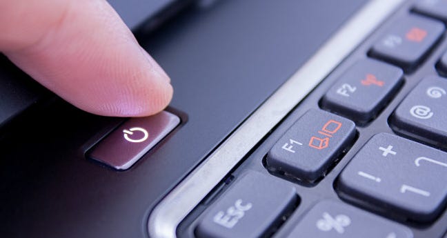 Sebuah jari menekan tombol power laptop.