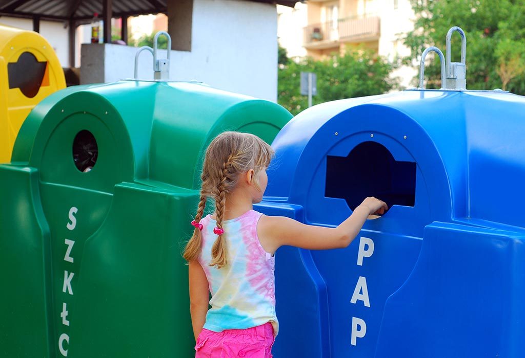Seorang anak membuang kertas ke tempat sampah daur ulang