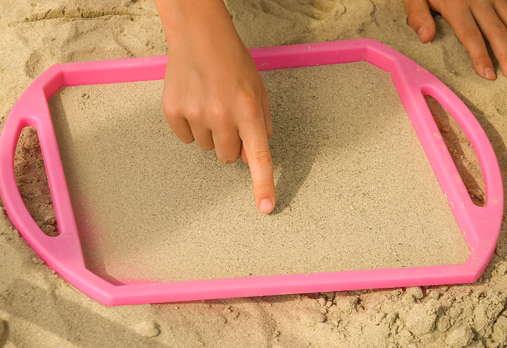 Anak menulis di pasir