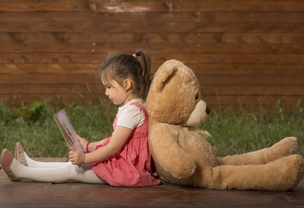 Anak membaca untuk mainan beruangnya