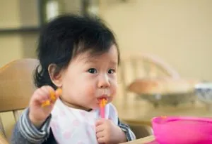 Seorang bayi perempuan makan ubi jalar tumbuk