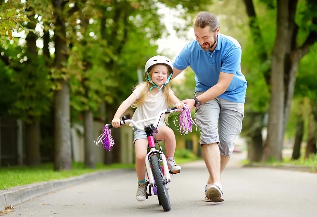 Seorang ayah mengajari putrinya cara mengendarai sepeda