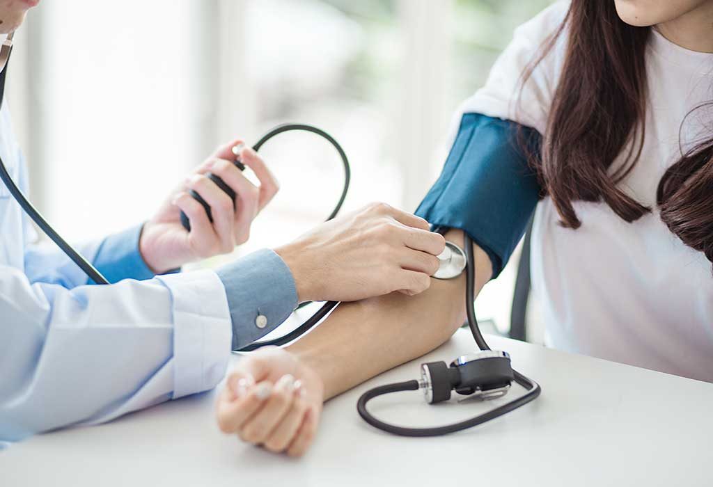 Seorang dokter memeriksa tekanan darah seorang wanita