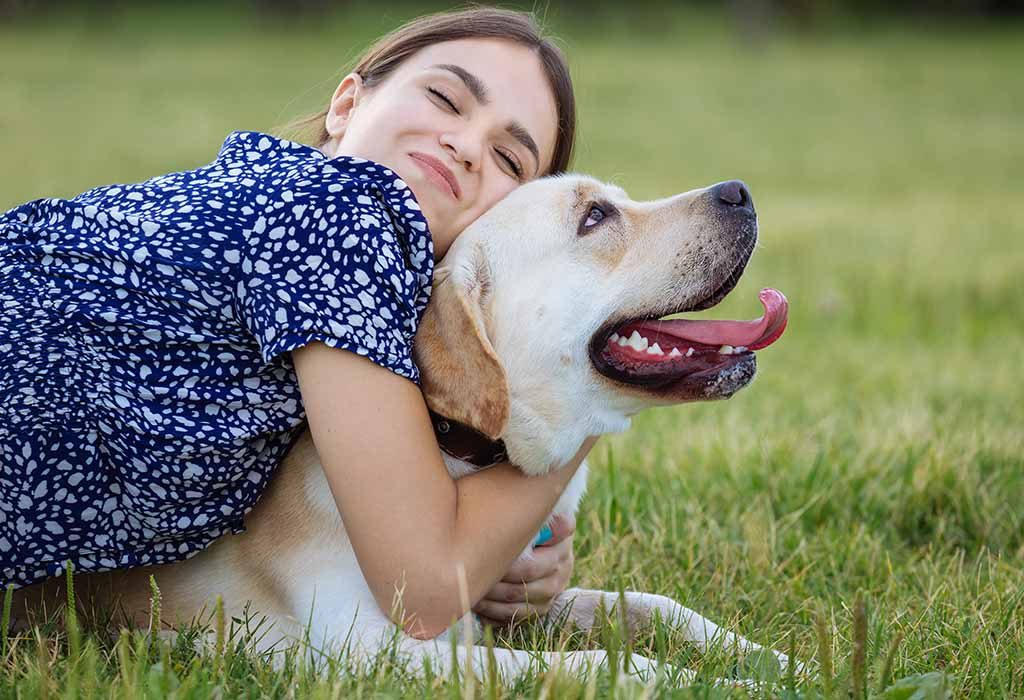 Seorang wanita bahagia memeluk anjingnya