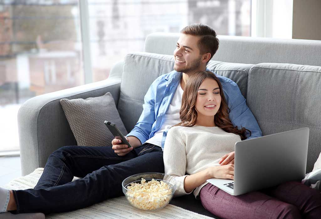 Seorang pria menonton TV dan wanita menggunakan laptop