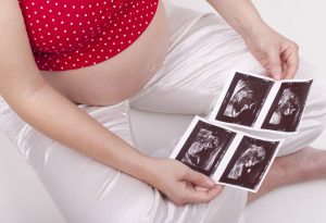 Seorang wanita hamil melihat dua pemindaian ultrasound