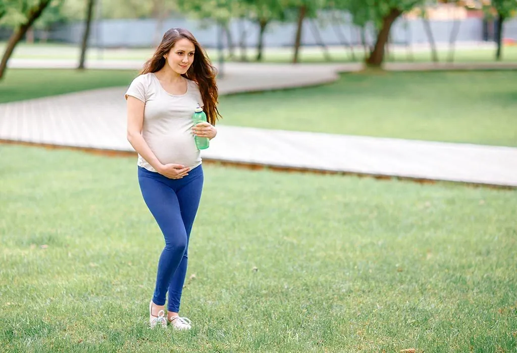 Seorang wanita hamil berjalan di taman